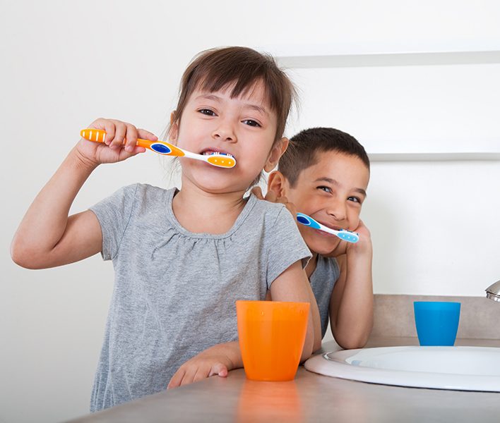 Brother and sister brushing their teeth